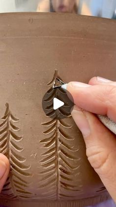 someone is decorating a cake with chocolate frosting and pine trees on the side