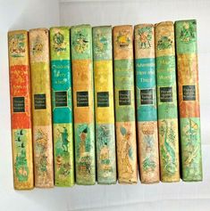 a row of old books sitting next to each other on a white surface with the covers painted green and yellow