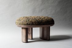 a wooden bench with a moss covered seat on it's legs, against a white background