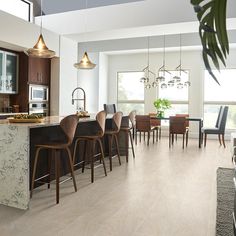 a kitchen and dining room with wood floors, marble counter tops and bar stools