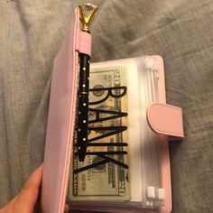 a pink wallet with some money in it and a pen sticking out of the pocket