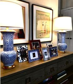 two lamps are sitting on a table with pictures in front of them and framed photos