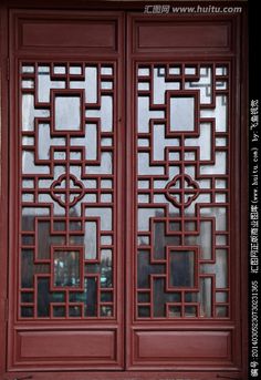 two red doors with intricate designs on the sides and side panels, in front of a building