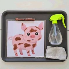 a tray that has some items on it including a bottle, pen and paper with a drawing of a pig