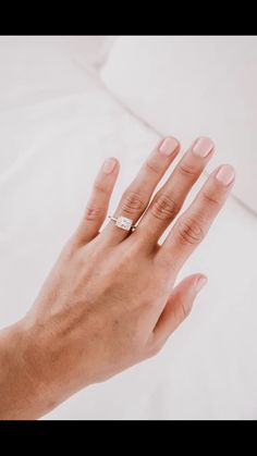 a person's hand with a wedding ring on top of their left hand, against a white background