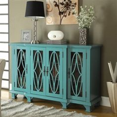 a blue cabinet sitting on top of a wooden floor next to a rug and vase