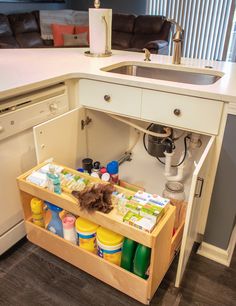 an open drawer in the middle of a kitchen counter with cleaning supplies and other items