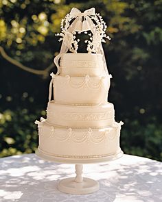 a three tiered wedding cake on top of a table with trees in the background