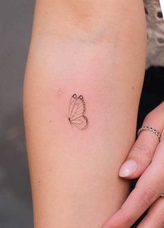 a woman's arm with a small butterfly tattoo on the left side of her arm