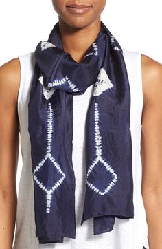 a woman wearing a white tank top and blue scarf with an arrow design on it