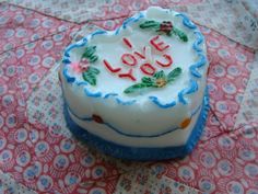 a decorated heart shaped cake sitting on top of a pink and blue tableclothed cloth