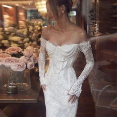 a woman in a white wedding dress standing next to a vase with flowers on it