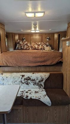 a living area with a couch, table and bed in the back ground on wheels