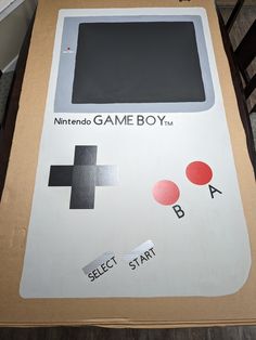 an old nintendo game boy box sitting on top of a wooden table with stickers