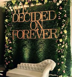 a white couch sitting in front of a green wall with flowers and words on it