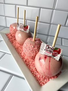 three candy apples are on a plate with pink sprinkles