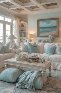 a living room filled with white furniture and blue pillows on top of it's couches