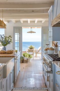 an open kitchen with white cabinets and wooden floors next to the ocean in front of it