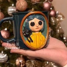 a hand holding a coffee mug with a doll on it