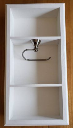 an open white box with a metal hook in the middle and two shelves on each side