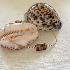 These beautiful tiger cowrie pieces are fused with mother of pearl so both sides are gorgeous. They are accented with freshwater seed pearls and woven onto braided waxed cord. Waxed cord is strong and waterproof🌊 Perfect for women with an active lifestyle.🧜🏻‍♀️ The cowrie pieces measure 5/8" by 3/8". Finished with a mother of pearl button clasp. Cowrie shells are from nature so each piece will be slightly different and unique.﻿💙Handmade by me with love in coastal Southern Maryland.💙Carefull Casual Adjustable Shell Jewelry, Cowrie Shell Beaded Bracelets As Gift, Shell-shaped Beaded Bracelets For Beach Season, Handmade Cowrie Shell Decor, Adjustable Shell Beaded Bracelets For Beach Season, Bohemian Beaded Bracelets With Adjustable Shell, Handmade Shell Beaded Bracelets, Artisan Hand Wrapped Beaded Bracelets For Beach, Bohemian Adjustable Shell Beaded Bracelets