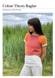 a woman standing in front of tall grass wearing an orange and pink top with short sleeves