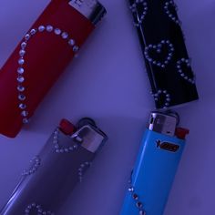 three different colored lighters with pearls on the top one is red, one is blue