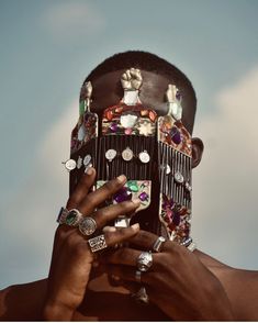 a person with rings on their head holding something in front of his face and looking up at the sky