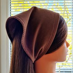 a mannequin head wearing a brown hat with pleated fabric on the top