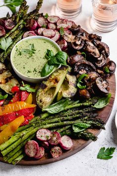 a platter with asparagus, radishes and other vegetables