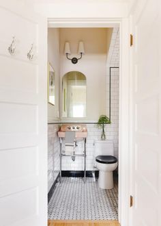 an open door leading to a bathroom with a toilet, sink and mirror in it