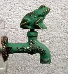 a green faucet with a frog figurine on it's side