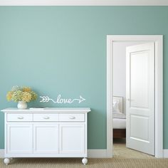 an empty room with a white cabinet and blue wall painted in teal, green and white