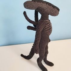 a crocheted cat with a hat on it's head is standing in front of a blue wall