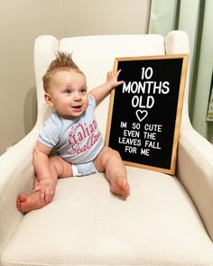 a baby sitting on a chair with a sign in front of him that says 10 months old