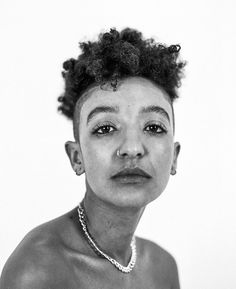 a black and white photo of a woman with short hair wearing a necklace on her neck