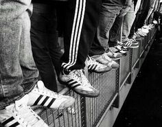 several pairs of tennis shoes are lined up on a fence in front of spectators at a sporting event