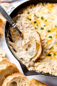 a skillet filled with cheesy bread and dip next to garlic bread slices