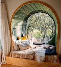 a bedroom with a circular window in the middle and pillows on the bed below it