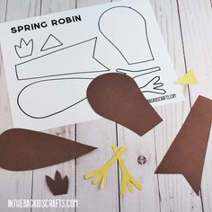 paper cut out of the shape of a bird and other crafting supplies on a white wooden surface