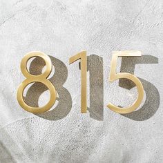 the number eighty five is shown in gold on a white background with shadows from it