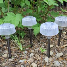 three glass garden lights sitting on the ground