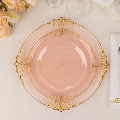 a pink plate sitting on top of a white table next to silverware and flowers