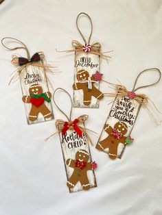 three wooden tags decorated with gingerbreads and christmas decorations are hanging on a white sheet