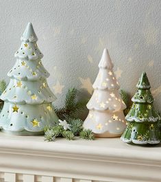 three ceramic christmas trees sitting on top of a mantle