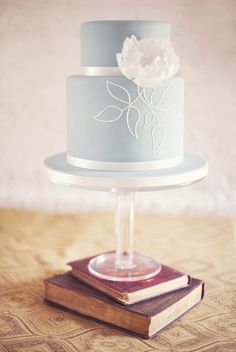 a three tiered cake sitting on top of a wooden table next to a stack of books