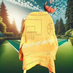 an orange crocheted sweater with a basketball on top and trees in the background