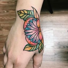 a woman's hand with a colorful flower tattoo on the left side of her wrist