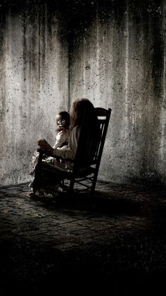 a black and white photo of a woman sitting on a chair in front of a wall