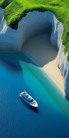 a boat is floating in the water near a large rock formation with grass growing on it